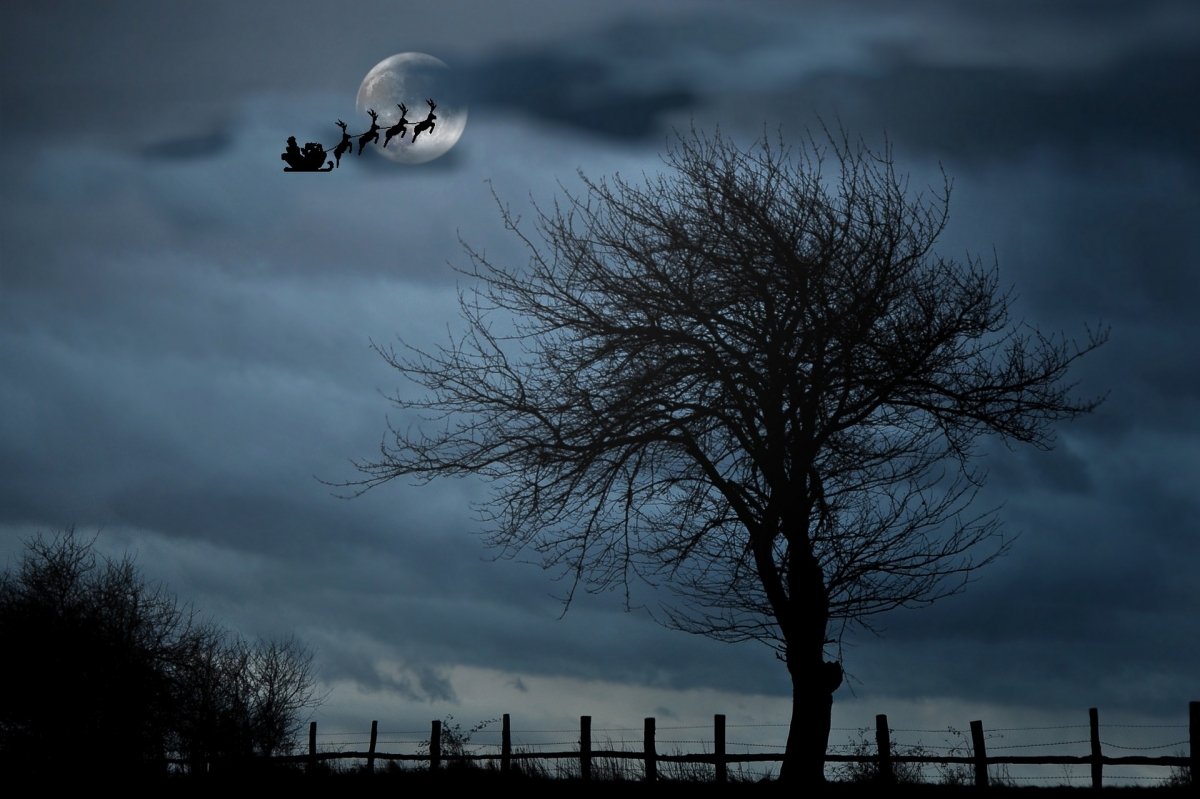 Papá Noel en su trineo y con sus renos surcando los cielos