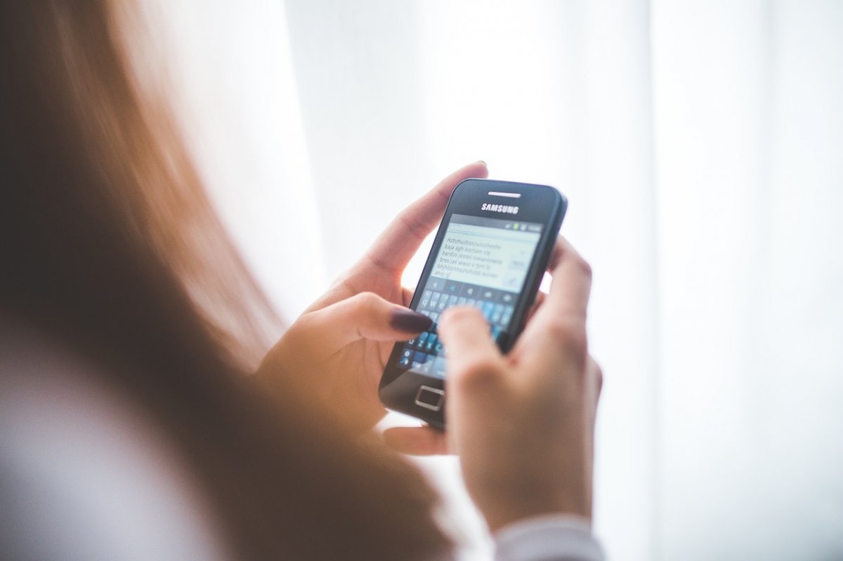 Una mujer escribiendo en su teléfono Android