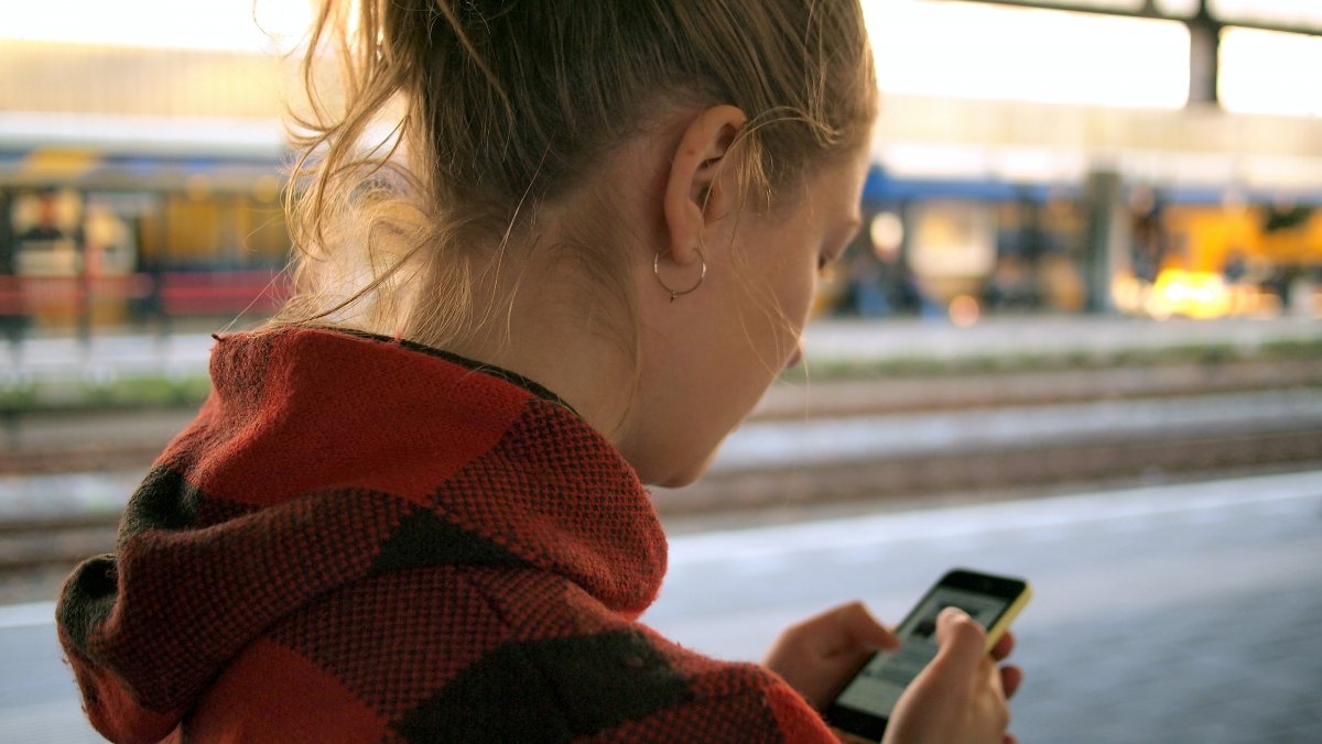 Una usuaria envía mensajes desde una estación de tren durante un viaje